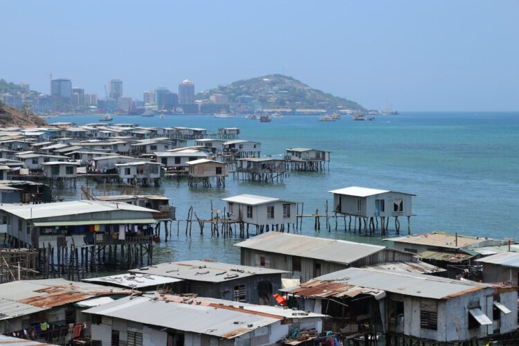 Coastal panoramic view of houses on stilts in foreground and Port Moresby city in background